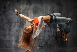A dancer does a move with her hand on the ground.