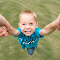 Panning photo of a boy spinning around holding hands with his Dad.