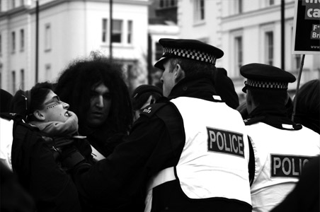 Photo of a riot in the UK with police shoving people.