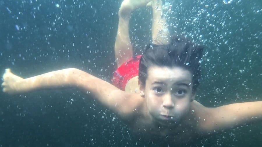 An photo of a boy swimming underwater.