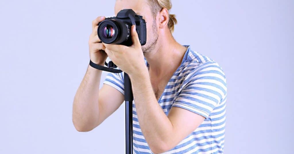 Handsome photographer with camera on monopod