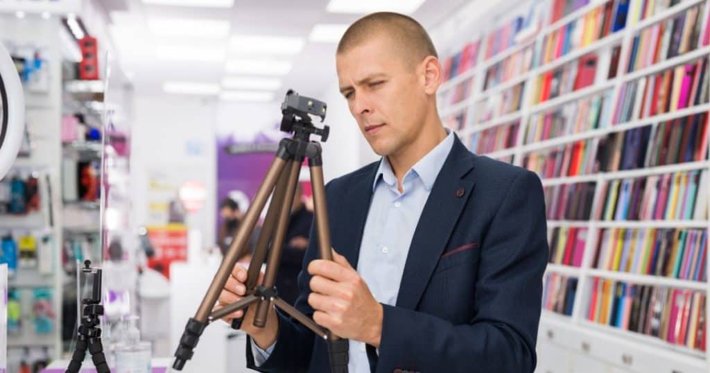 Male customer buying tripod at the multimedia store