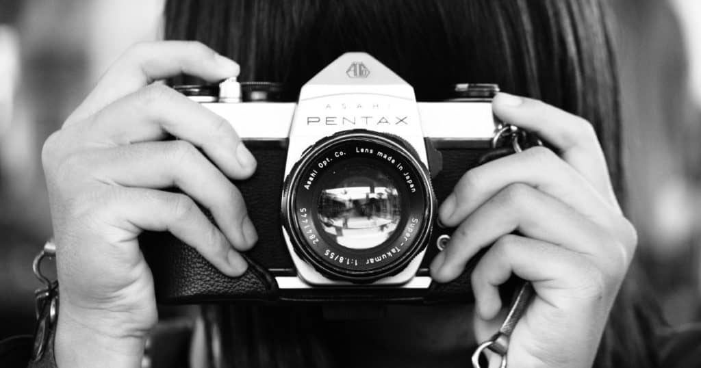 woman holding dslr camera in grayscale photography
