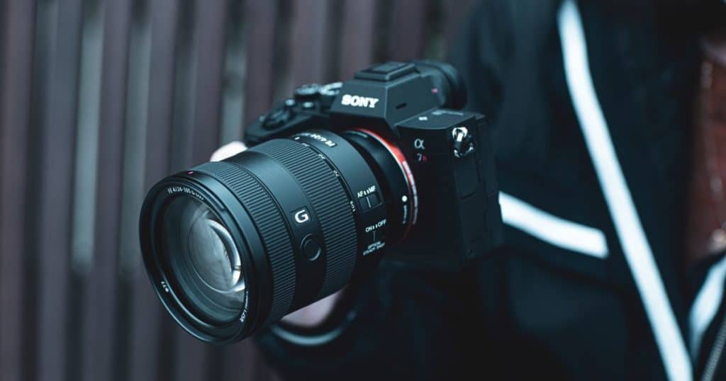 man holding a black sony camera in hand