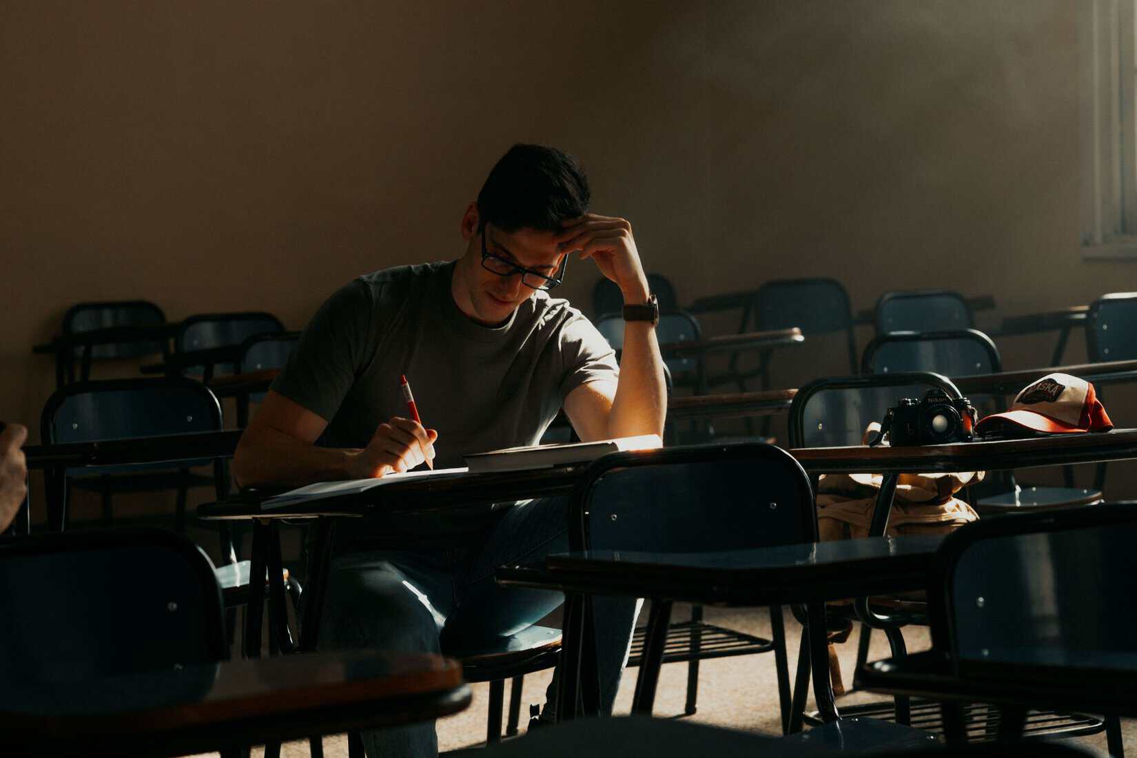 Student studying in a classroom with a camera nearby
